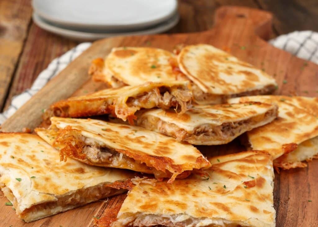 quesadillas with pulled pork on board with plates
