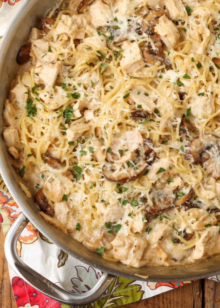 Chicken tetrazzini in a large stainless steel skillet on a floral towel