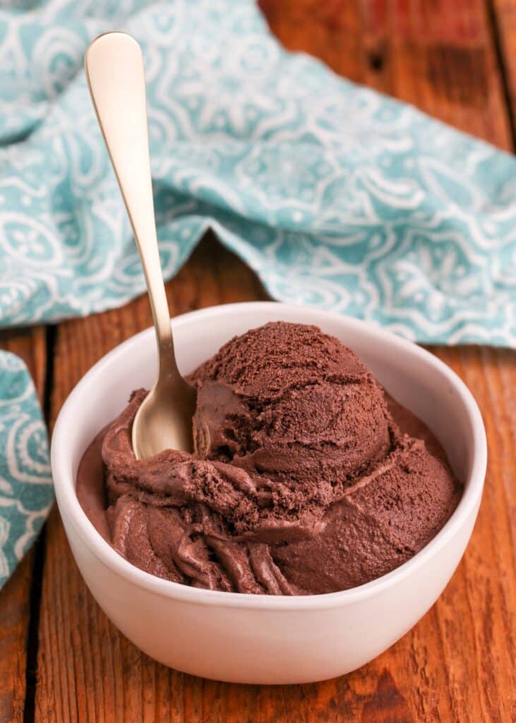 Dark Chocolate Ice Cream with spoon in white bowl and blue and white linen
