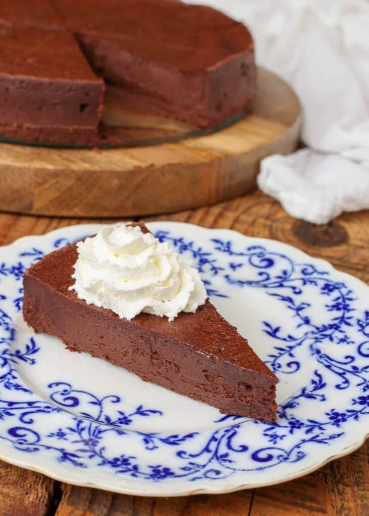 flourless chocolate cake topped with whipped cream on blue and white plate