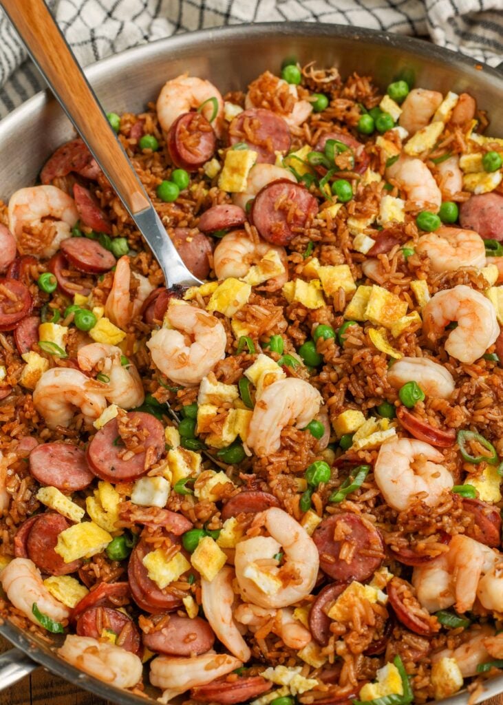 kielbasa fried rice in skillet with serving spoon