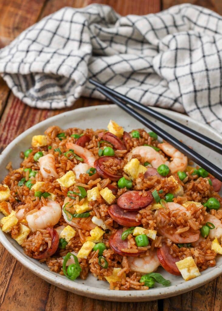 fried rice with shrimp and kielbasa on pottery plate with chopsticks