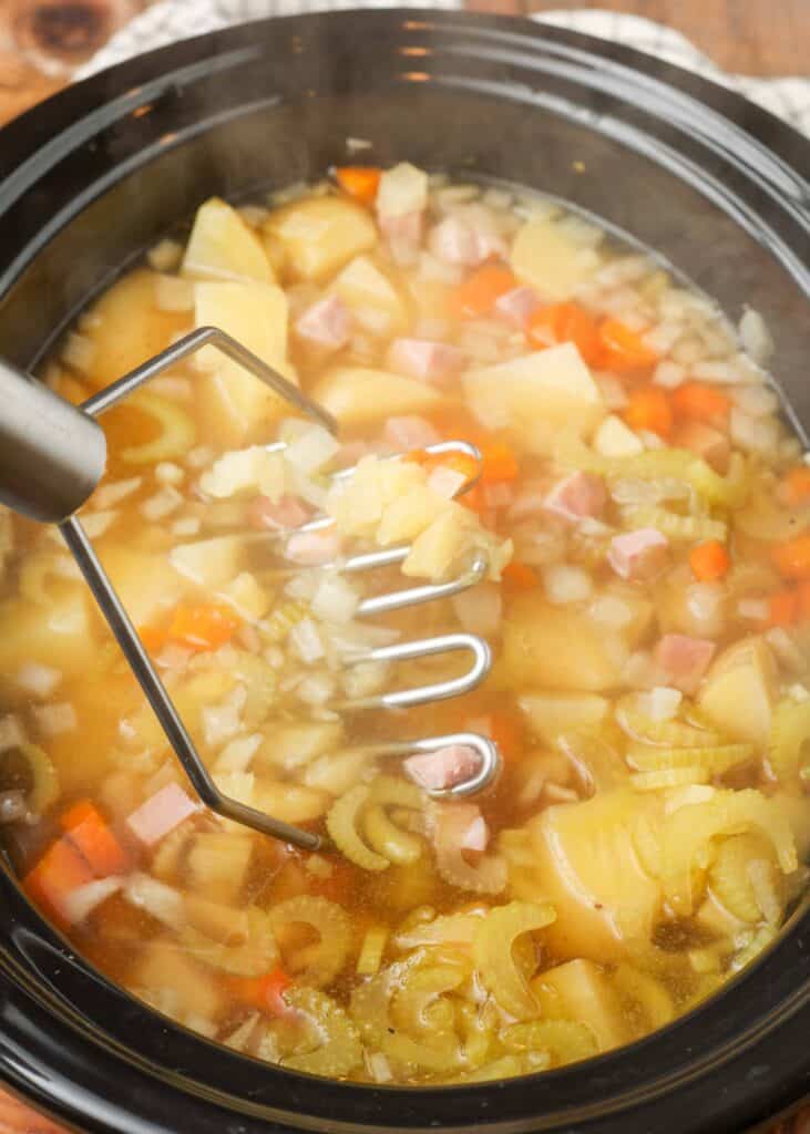slow cooker ham and potato soup mashed in a cooking pot