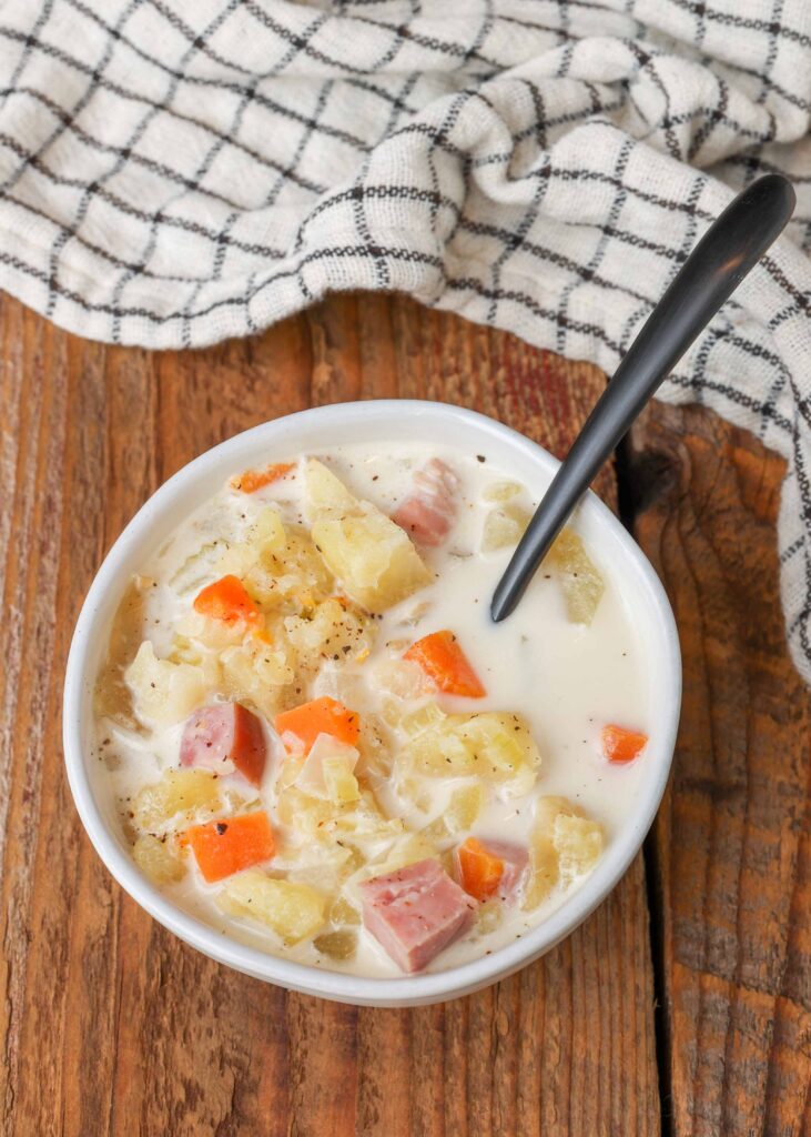 Zuppa di prosciutto e patate a cottura lenta in ciotola bianca con cucchiaio