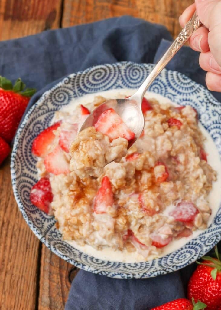 oatmeal with strawberries in blue and white bowl with spoon