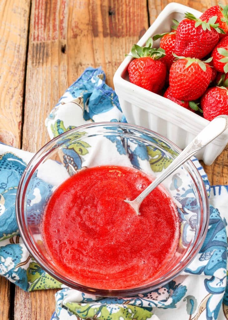 easy strawberry sauce in clear bowl with spoon and floral napkin