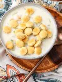 clam chowder topped with oyster crackers in pottery bowl on wooden plate