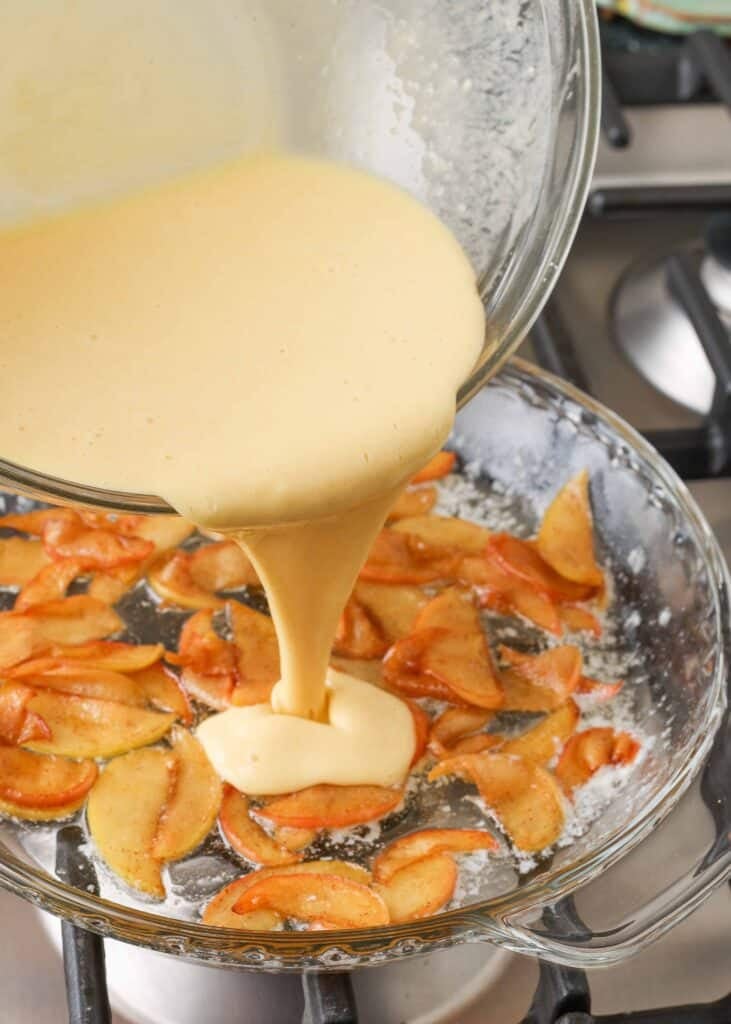 la mezcla de huevo se vierte sobre las rodajas de manzana con especias en el fondo del molde para pastel