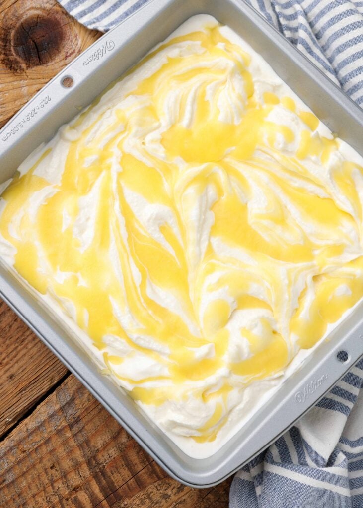 una foto dall'alto in basso di una vaschetta piena di gelato condita con una salsa al limone giallo