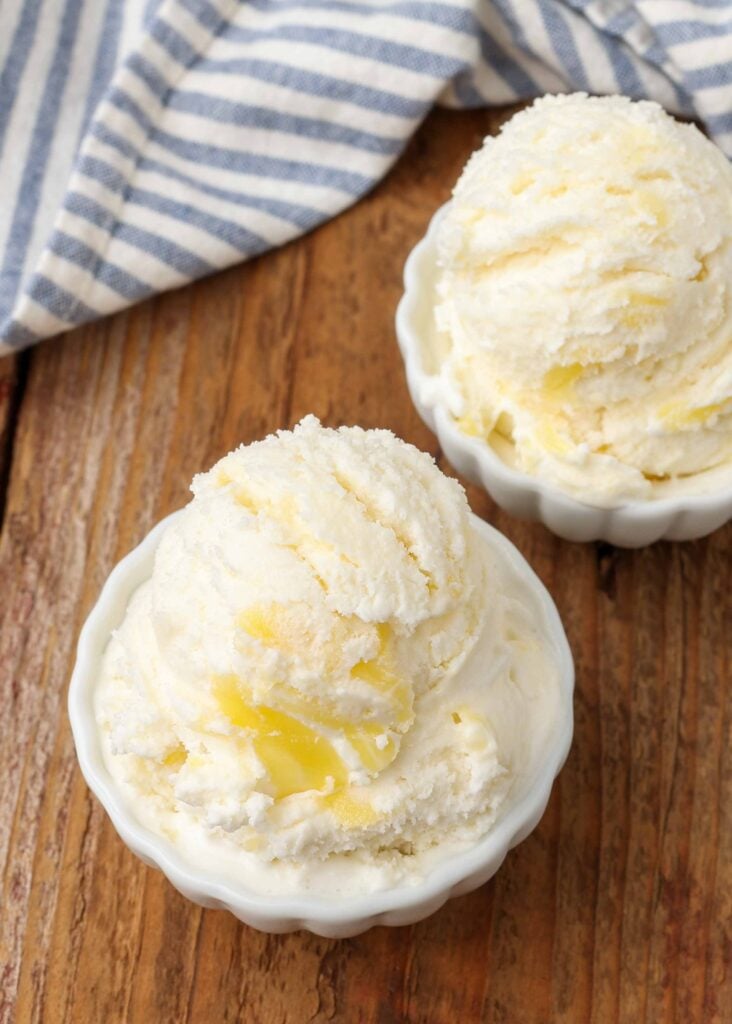 bolas de helado de limón en un tazón blanco sobre una mesa de madera con toallas de té en el fondo