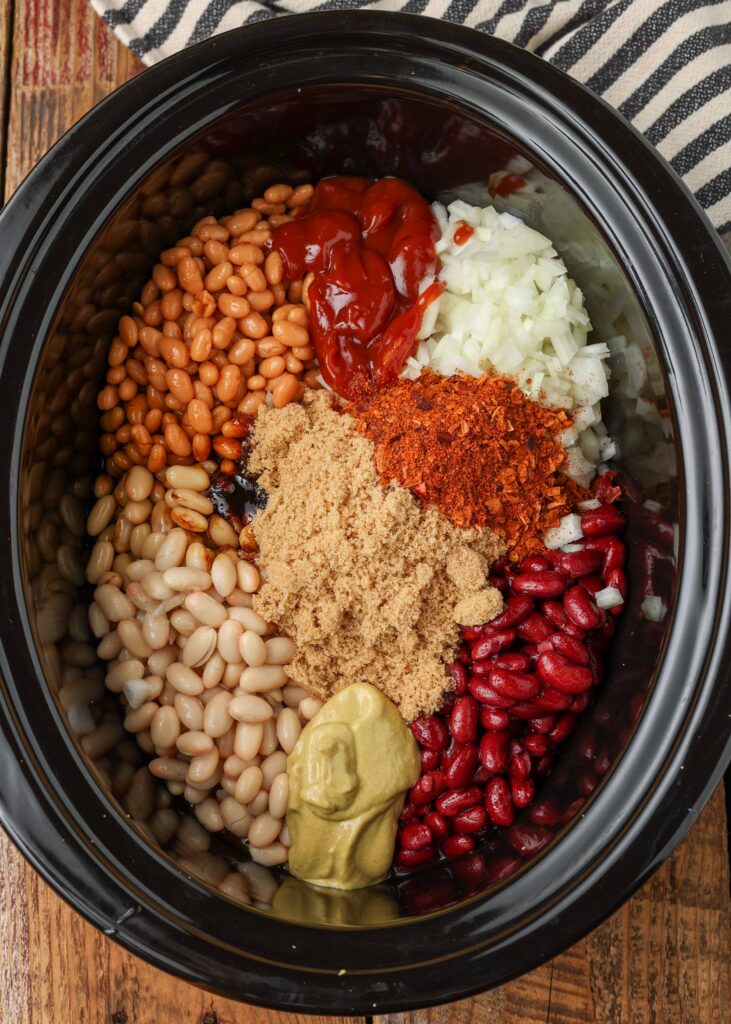 all of the ingredients have been added in a visually appealing manner with each type of beans and seasoning distinctly visible in this black crockpot