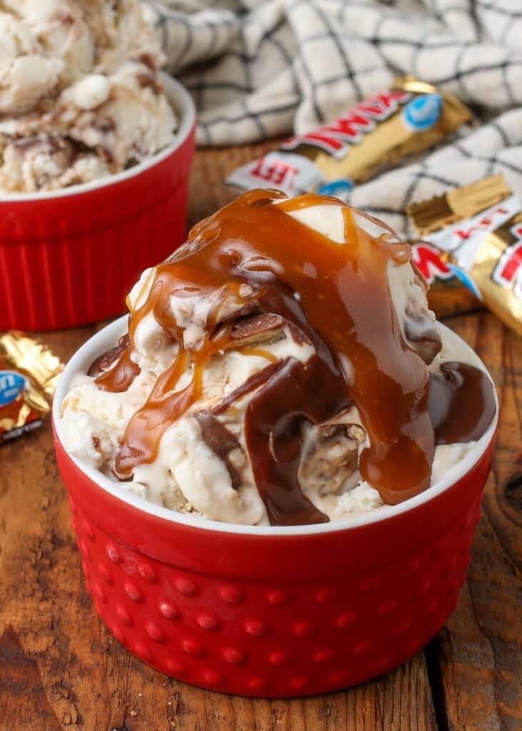 an avalanche of caramel sauce and hot fudge adorn this scoop of Twix Ice Cream in a red ramekin