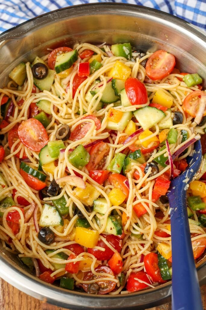 The dressing has been added to a pasta and vegetable salad in a metal bowl