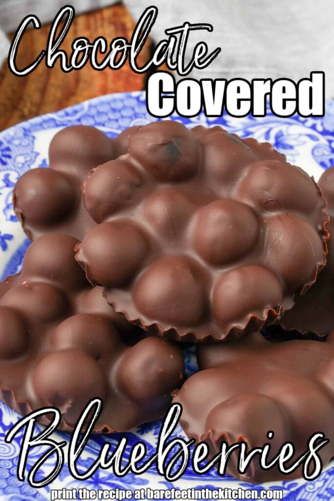 Blueberries covered in a dark chocolate layer, stacked in a blue and white bowl with a floral pattern
