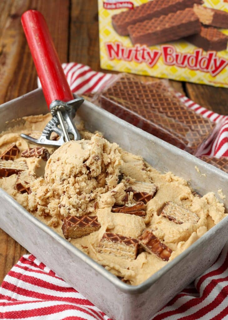 a metal loaf pan full of nutty buddy ice cream and a red handled ice cream scoop