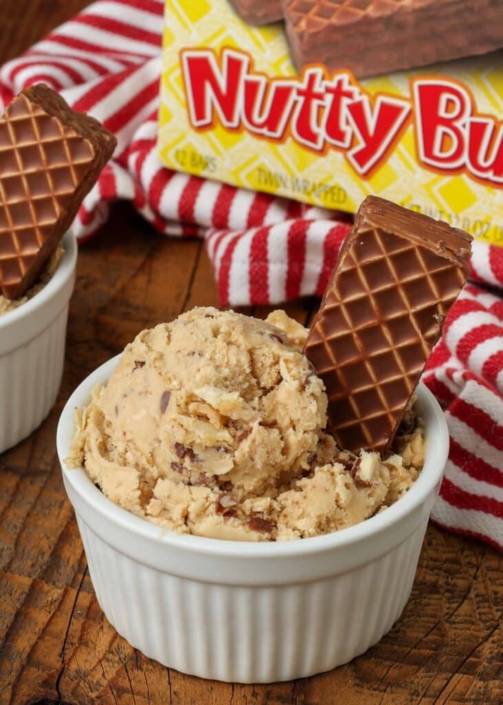 a vertically aligned photo of a scoop of nutty bars ice cream in a white ramekin with a box of nutty buddy bars visible in the background