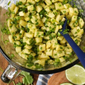 pineapple salsa in mixing bowl with lime wedges