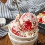 Strawberry Shortcake Ice Cream with gold spoon in white bowl on wooden table