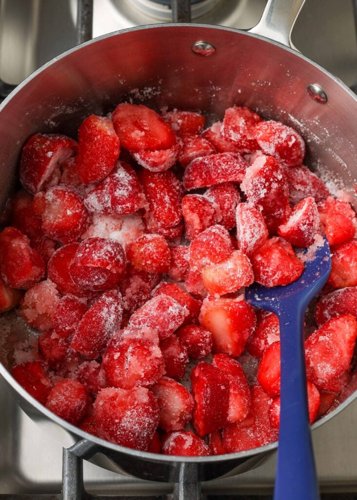 frozen strawberries with sugar in saucepan