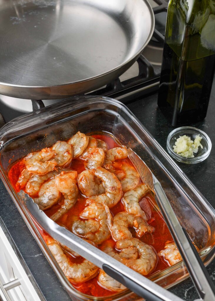 chili garlic marinated shrimp in container with tongs