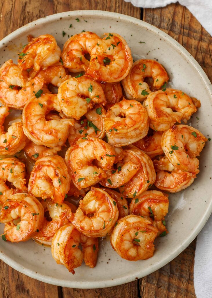 cooked shrimp on white pottery plate on wooden table