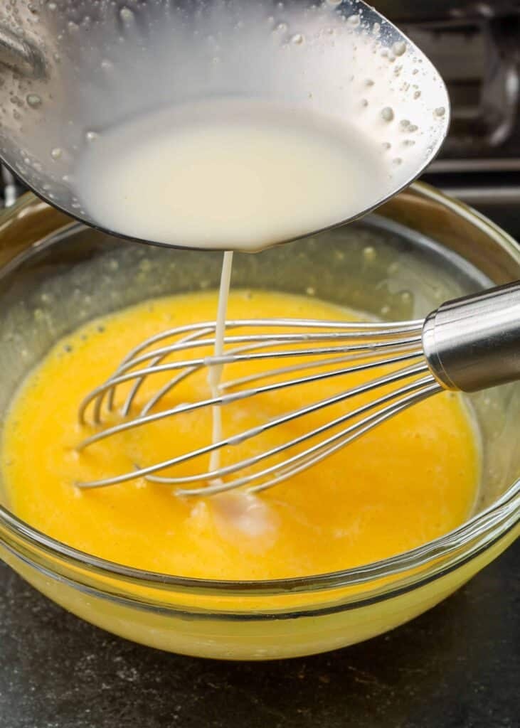 Eggs and cream whisked together in a glass bowl