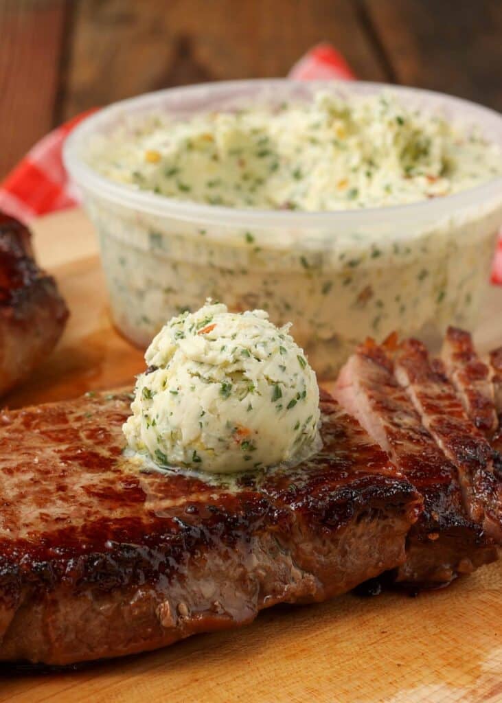 cowboy butter over grilled steak on cutting board