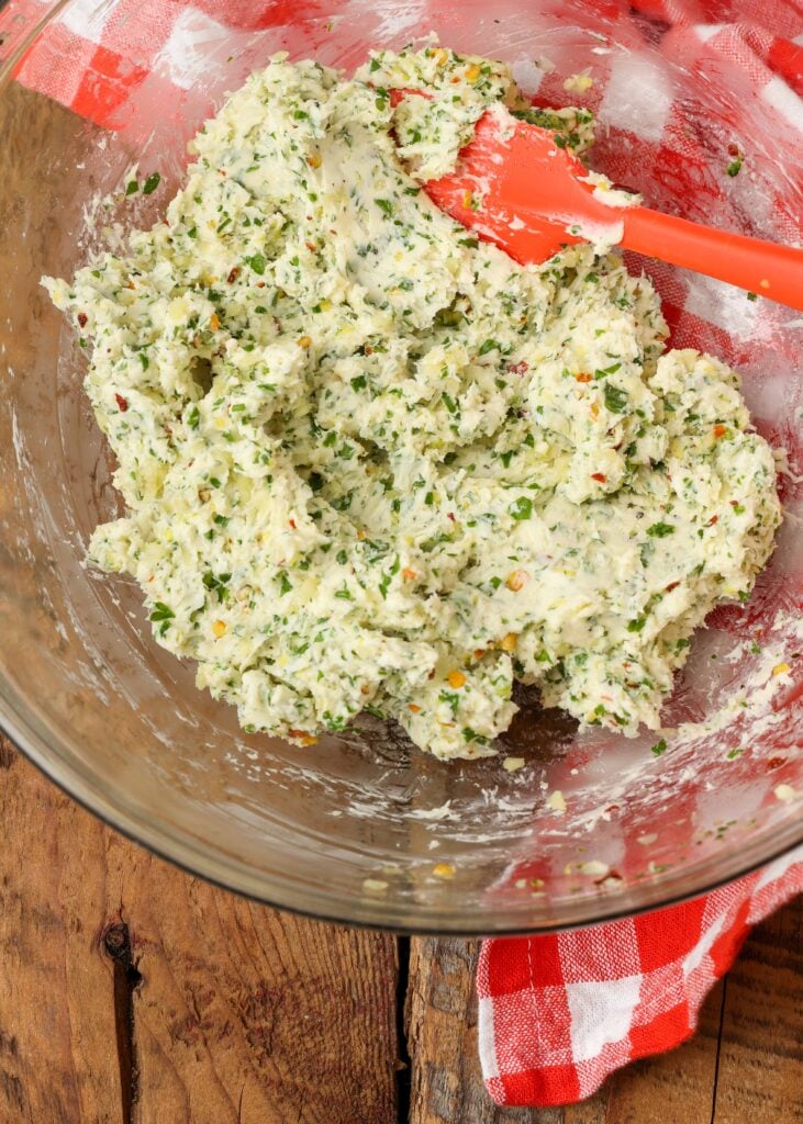 garlicky herb compound butter mixed together in bowl on wooden table