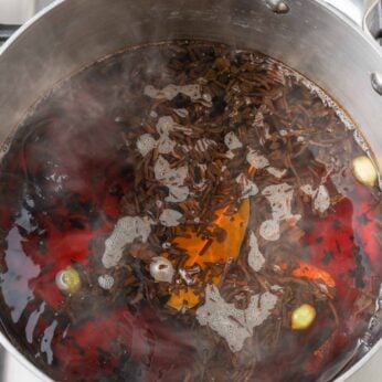 spices and black tea leaves steeping in pan