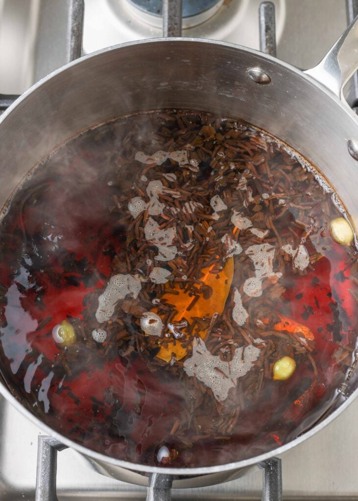 spices and black tea leaves steeping in pan