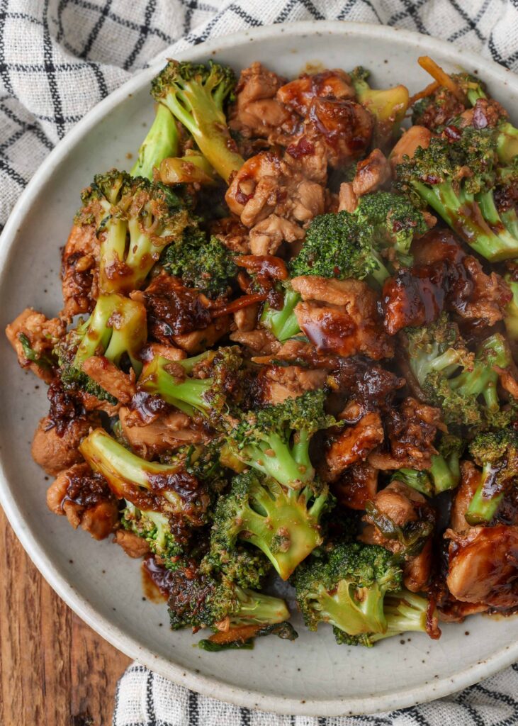 A plate on a wooden table with chicken and broccoli