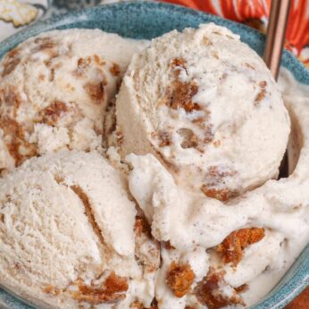 Overhead close-up of oatmeal cream pie ice cream, served in a blue bowl with a copper spoon