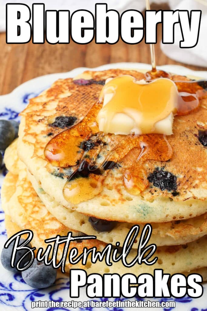 a tropical up shot of pouring syrup onto a stack of pancakes, with white lettering over the image that reads: "Blueberry Buttermilk Pancakes"