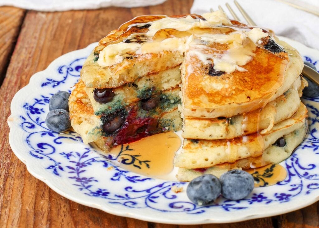 A stack of warm, fluffy blueberry pancakes on a white and blue plate