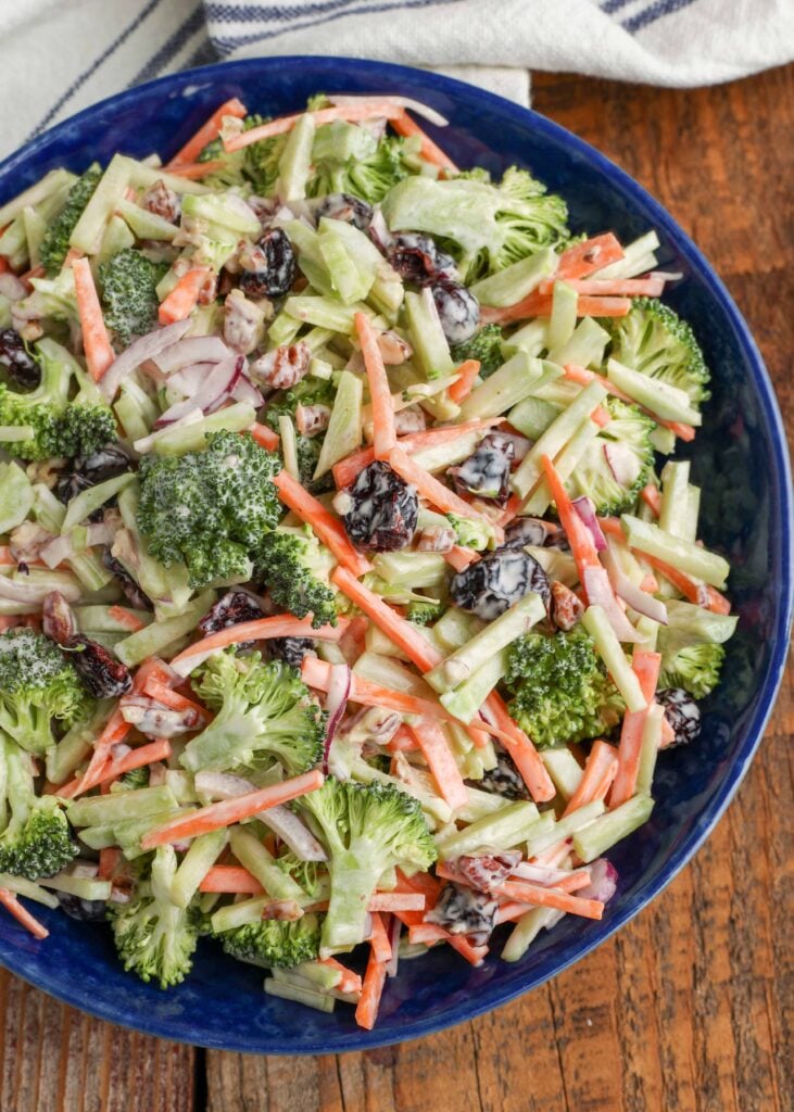 close up of broccoli slaw in blue bowl on wooden table
