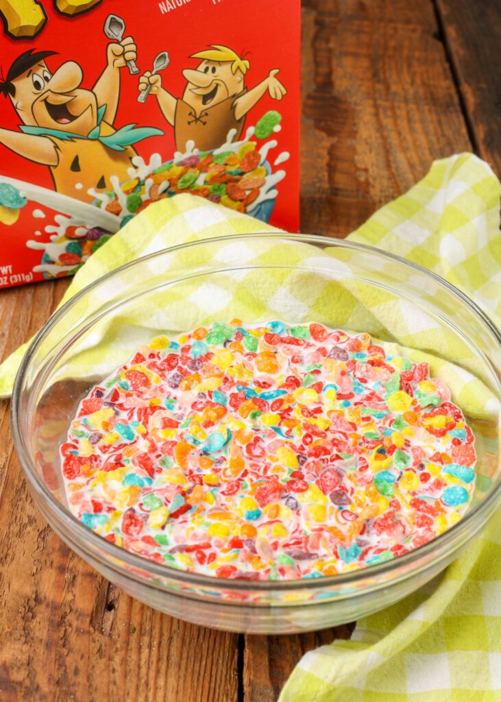 Overhead shot of Fruity Pebbles cereal and milk in a glass bowl