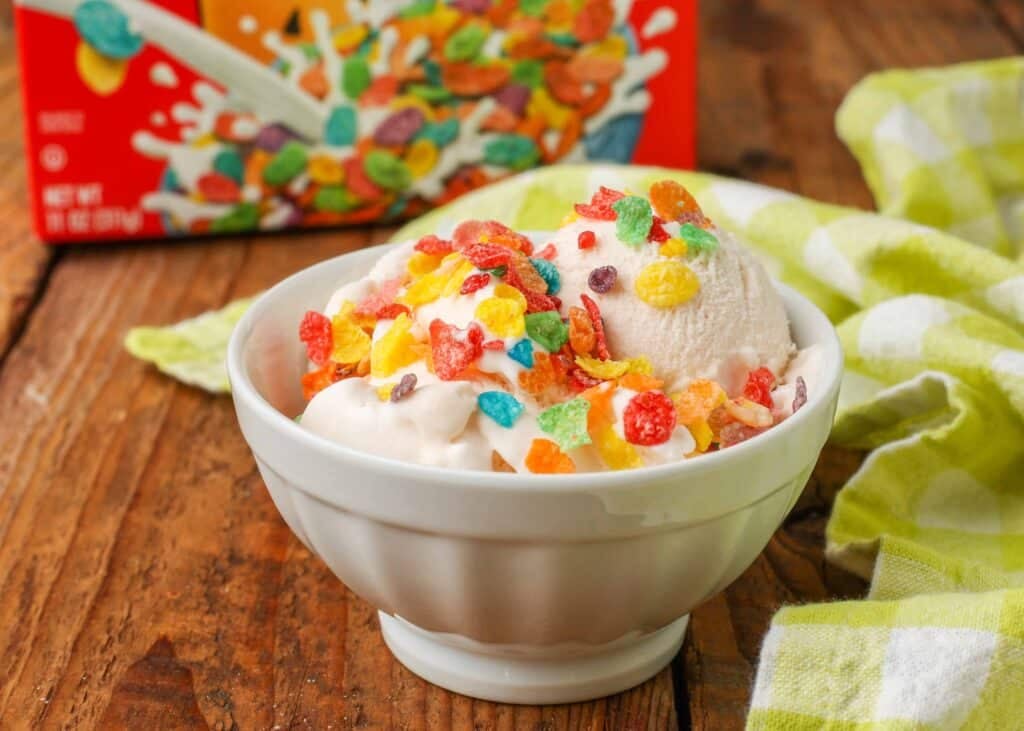 Horizontal shot of Fruity Pebbles Ice Cream topped with Fruity Pebbles cereal, served in a small white bowl