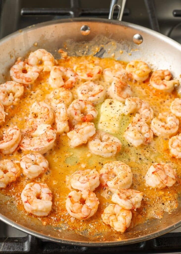 Overhead shot of buttery shrimp and garlic in a stainless steel skillet