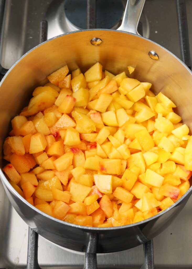 Overhead shot of chopped and diced peaches in a stainless steel skillet