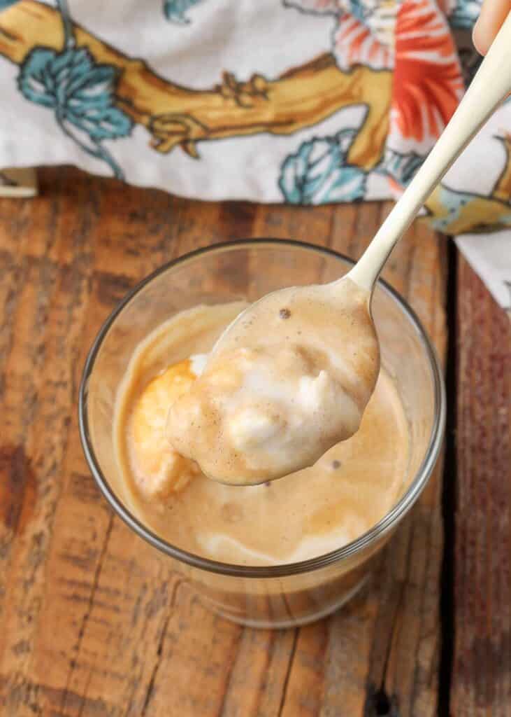 Overhead shot of a spoonful of affogato, poised over the mouth of the glass