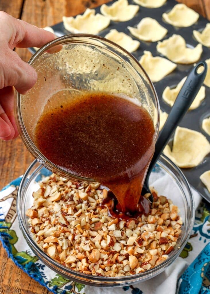 honey mixture being poured into chopped nuts