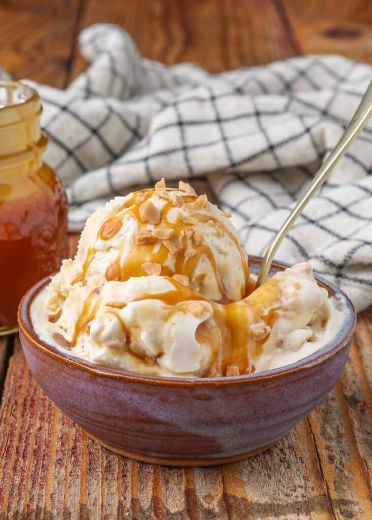 Toffee ice cream with caramel syrup and caramel pieces, served with a silver spoon