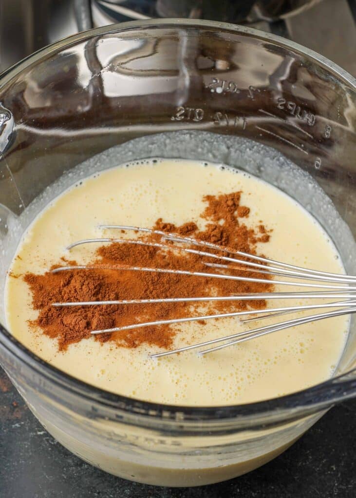 Whisking ground cinnamon into mixture in glass bowl