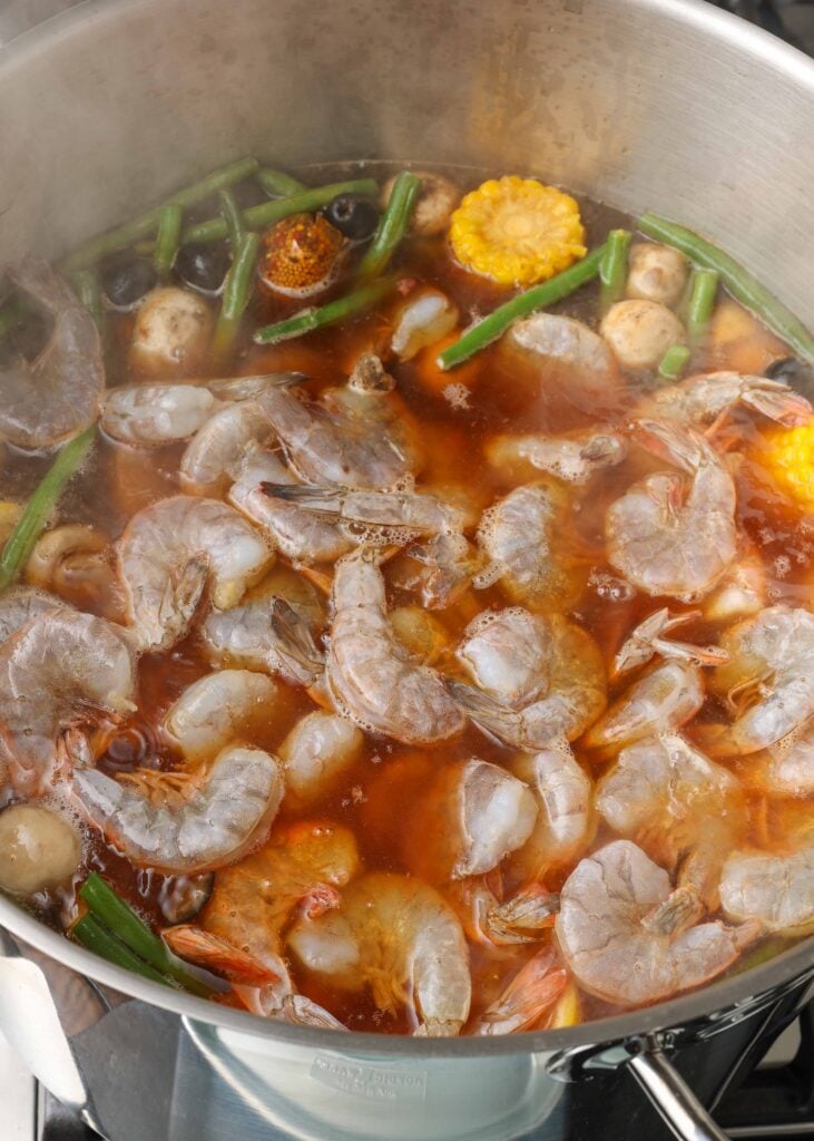 Overhead shot of shrimp, vegetables, and spices in pot