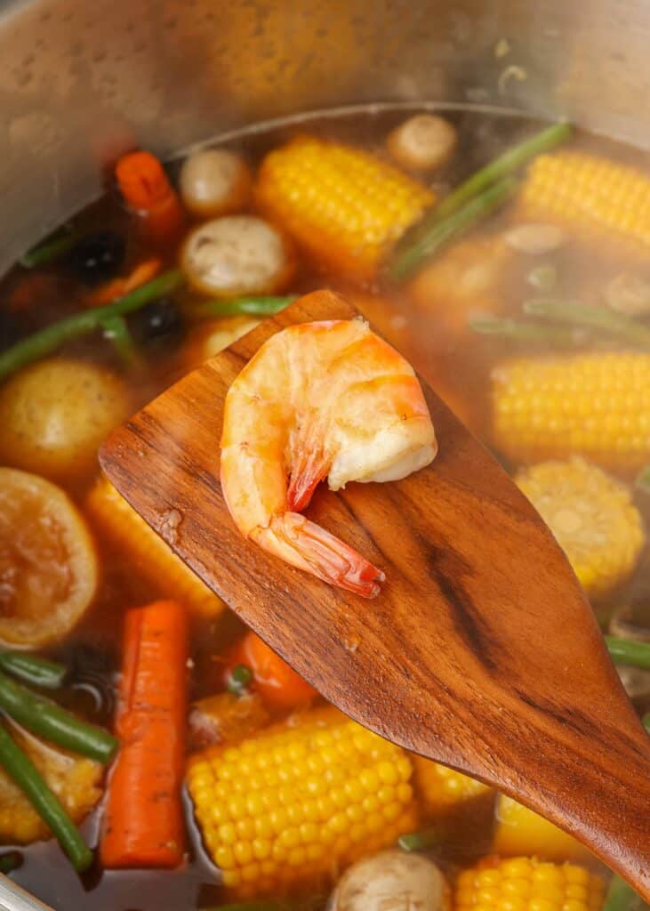 Shrimp from pot, held on a wooden spoon