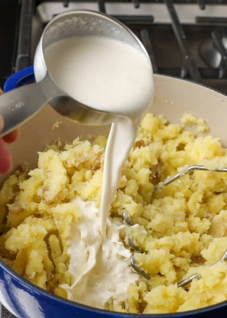 Pouring heavy cream into mashed potatoes