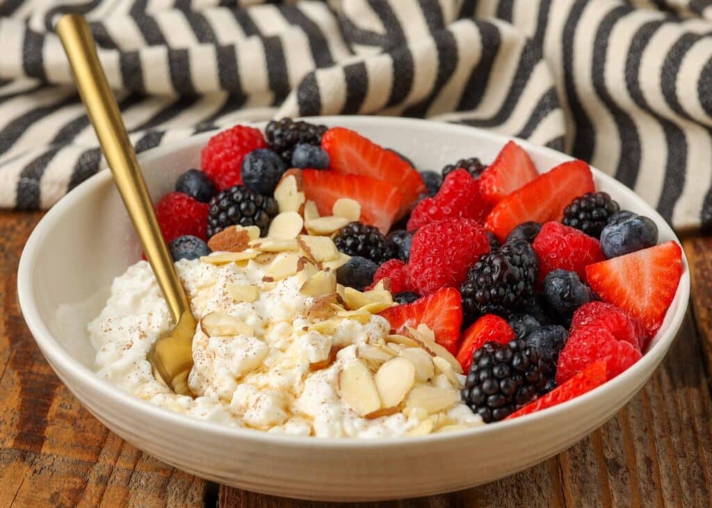 Vertical shot of cottage cheese in bowl with honey, almonds and fruit