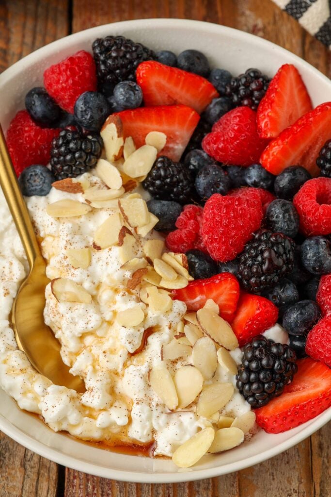 Overhead shot of cottage cheese, berries, almonds, and honey