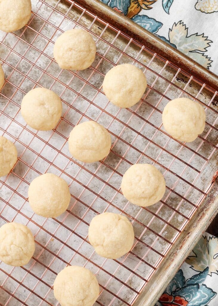 small almond butter cookies on a cooling rack over a sheet pan