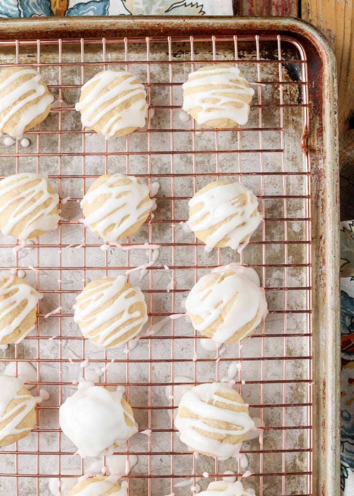 small glazed almond butter cookies on a cooling rack over a sheet pan